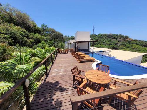a wooden deck with tables and chairs next to a swimming pool at Casa Absolute Summer Breeze e Piscina in Morro de São Paulo