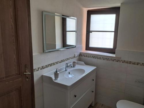 a bathroom with a sink and a mirror and a window at La casa gialla, Rosazza, Biella in Rossaza