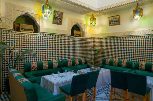 a restaurant with green seats and a table in a room at Riad Yamna Fez in Fès
