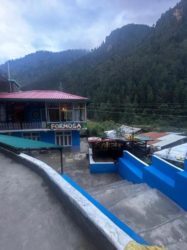 a view of a building with mountains in the background at Formosa cafe & hostel in Kasol