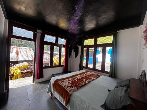 a bedroom with a bed in a room with windows at Formosa cafe & hostel in Kasol