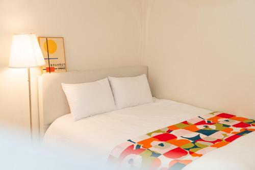 首尔Dohwa Stay - New Open AREX, 3mins to Gongdeok Station的一张白色的床,上面有五颜六色的毯子
