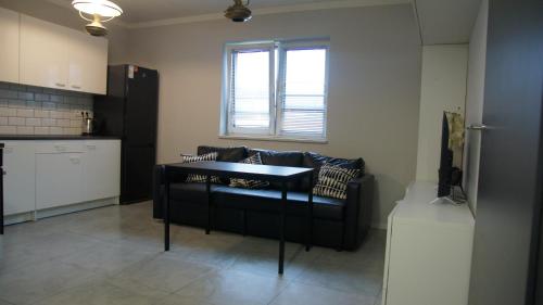 a living room with a black couch and a kitchen at Mia Mia House in Katowice