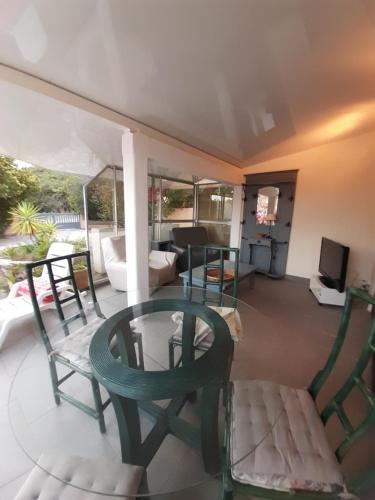 une terrasse couverte avec des chaises, une table et une télévision dans l'établissement Vermentinu T1 bis 50 m plage du Ruppione, à Pietrosella