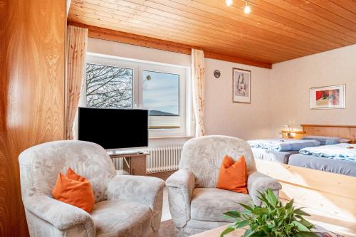 two chairs and a television in a room with two beds at Lorenzenhäusle Titisee-Neustadt in Titisee-Neustadt