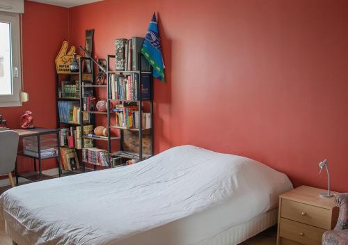 a red bedroom with a bed and a book shelf with books at Spacious home near Canal and Stadium with Wifi in Reims