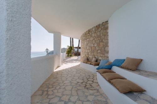 a living room with white walls and a stone wall at Villa Bora Montiboli by Buccara in Villajoyosa