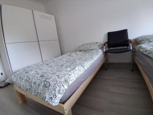 a bedroom with a bed and a chair in it at Pension Ronnys wilde Wiese in Belgershain