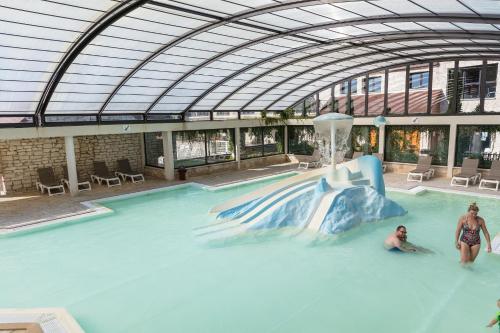 two people in a swimming pool with a water slide at Camping La Croix du Vieux Pont in Berny-Rivière