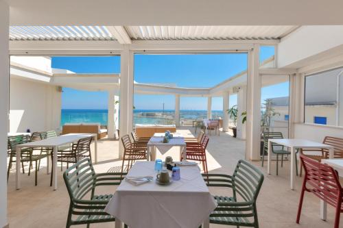 een restaurant met tafels en stoelen en uitzicht op de oceaan bij Marnik Luxury B&B in San Foca
