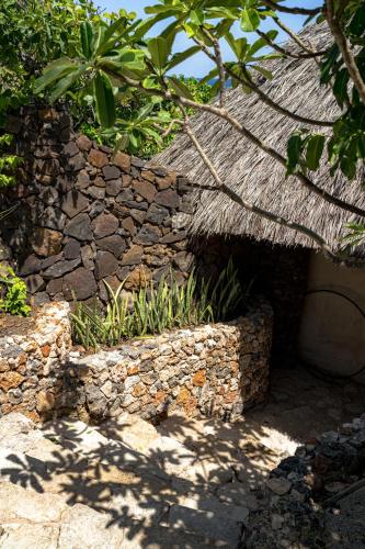 a stone building with a grass roof and plants at Bo'a Vida Rote in Nembrala