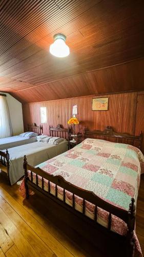 a bedroom with two beds and a wooden ceiling at Hospedaria 71 in Campo Alegre