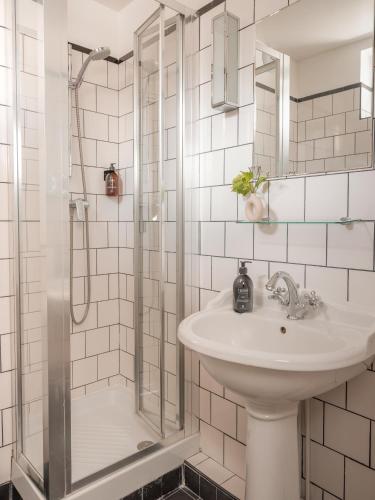 une salle de bain blanche avec un lavabo et une douche dans l'établissement Hôtel BASSS, à Paris