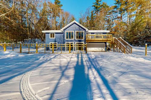 a blue house in the snow with a snow covered yard at Big St Germain Hideaway in Sayner