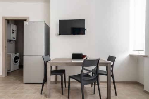 a kitchen with a table with chairs and a refrigerator at Scalo a MXP Verde Con Fatturazione disponibile in Somma Lombardo