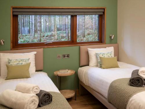 two beds in a room with a window at Forest of Dean Cabins - Forest Holidays in Staunton