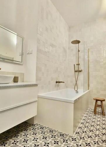 La salle de bains est pourvue d'une baignoire, d'un lavabo et d'un tabouret. dans l'établissement Appartement 45 m2,élégant rénové, centre historique, à Pézenas