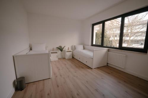 a white living room with a couch and a window at Ferienwohnung Kassel mit Ladesäule & Balkon in Kassel