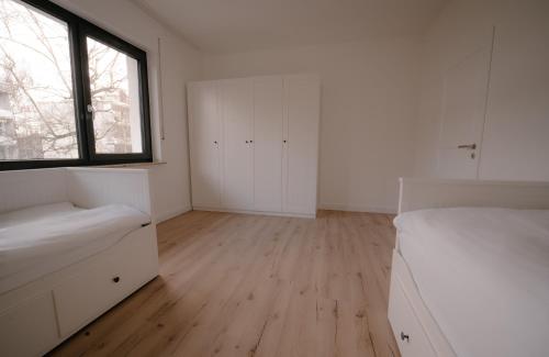 a bedroom with white furniture and a large window at Ferienwohnung Kassel mit Ladesäule & Balkon in Kassel