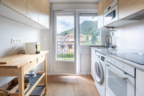 une cuisine avec lave-linge et sèche-linge et une fenêtre dans l'établissement Apartamento Urdaibai Busturia cerca de la playa, à Busturia
