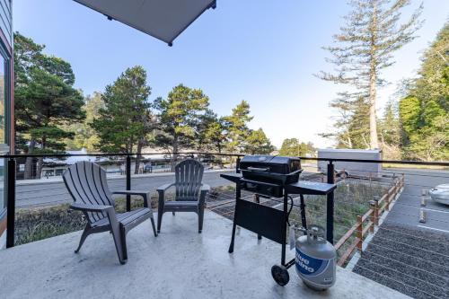 a patio with two chairs and a grill on a deck at Serenity at Deerhaven #B & #C in Gold Beach