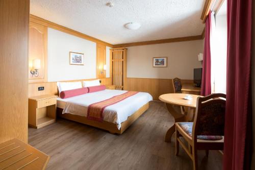 a hotel room with a bed and a table at Hotel Intermonti in Livigno