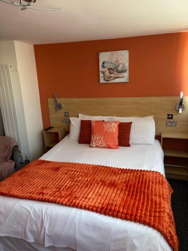 a bedroom with a large bed with an orange wall at The Beaucliffe Hotel in Blackpool