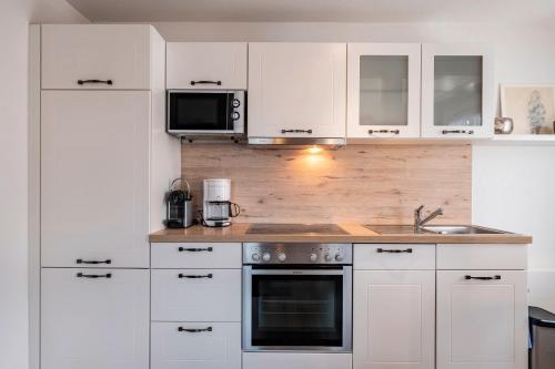 a kitchen with white cabinets and a sink and a microwave at Ferienwohnung Dachtler in Hinterzarten