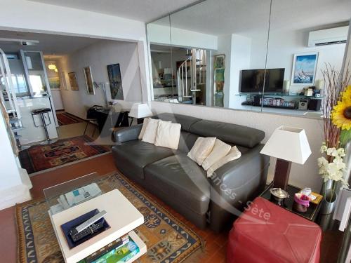 un salon avec un canapé en cuir et une télévision dans l'établissement Duplex avec double terrasse 1ere ligne de mer, wifi et climatisation, à Sète