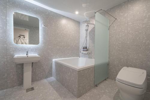 a bathroom with a tub and a sink and a toilet at Hotel Lavanda in Incheon