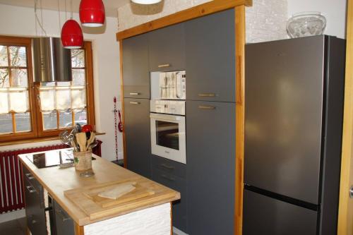 une cuisine avec un réfrigérateur noir et une cuisinière dans l'établissement la ferme de manu, à Saulxures