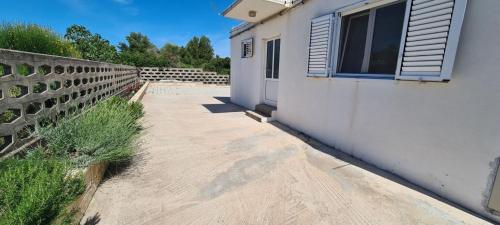 a sidewalk next to a white building with a window at House Karmela in Sućuraj