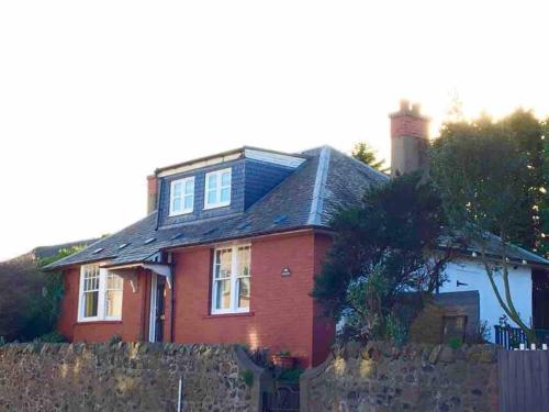 a red brick house with a fence in front of it at Family seaside home, easy access to Edinburgh in Kinghorn