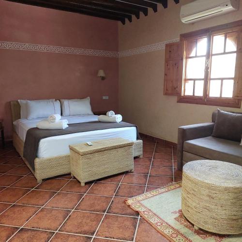 a bedroom with a bed and a chair and a couch at Chez Mamouchthka in Ourika