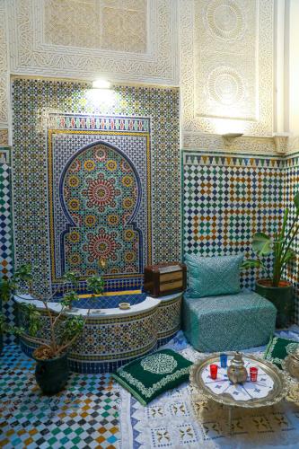 a room with a mosaic wall with a tub and a chair at Riad Yamna Fez in Fès