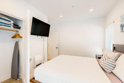 a white bedroom with a bed and a flat screen tv at Serenity at Deerhaven #A & #B in Gold Beach