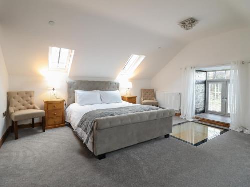 a bedroom with a bed and a chair and windows at Gaerau Bach in Llanbedr