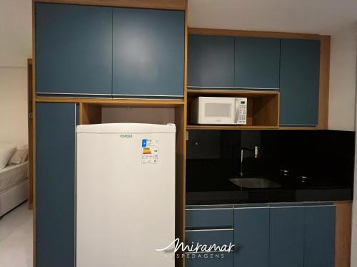 a kitchen with a refrigerator and a microwave at Vert House Jardim Oceania - Miramar Hospedagens in Tambaú