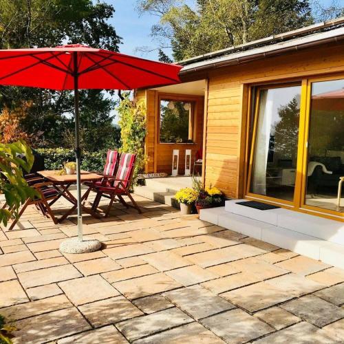 a patio with a table and a red umbrella at Ferienhaus Ilfeld in Ilfeld