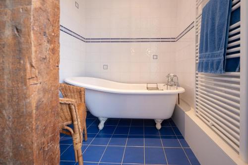 a white bath tub in a bathroom with blue tiles at Charming house Le Clos Marie in Châteaubourg