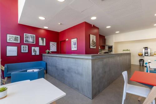 a bar in a restaurant with red walls at Study Hôtel Bordeaux Lormont in Lormont