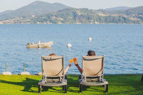 two people sitting in chairs by the water at Residence Casa e Vela in Oggebbio