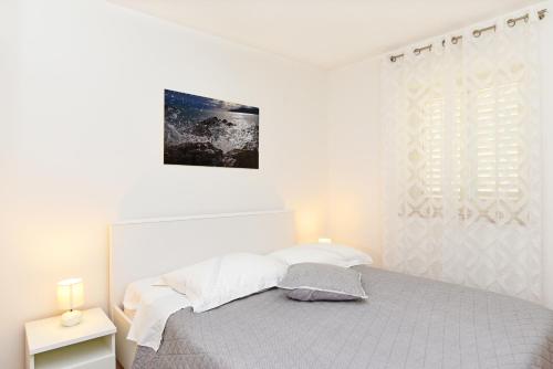 a white bedroom with a bed and a window at Seaview Apartment Bojan Rabac in Rabac
