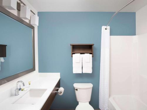 a bathroom with a white toilet and a blue wall at WoodSpring Suites Buford near Mall of Georgia-Lake Lanier in Buford