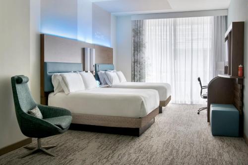 a hotel room with two beds and a chair at EVEN Hotel Pittsburgh Downtown by IHG in Pittsburgh