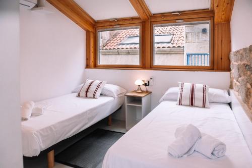 two beds in a room with a window at A 5 min de las Playas de Cangas by CABANA Rentals in Cangas de Morrazo