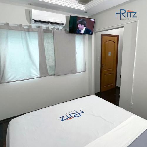 a room with a bed with a tv on the wall at Ritz Hostel in Araçatuba
