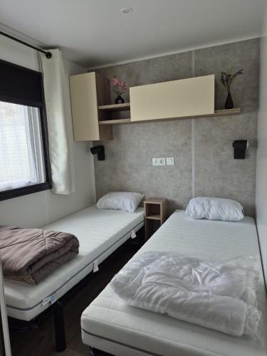 une chambre avec deux lits et une fenêtre dans l'établissement Le Domaine de Litteau 4 étoiles emplacement 434, à Litteau