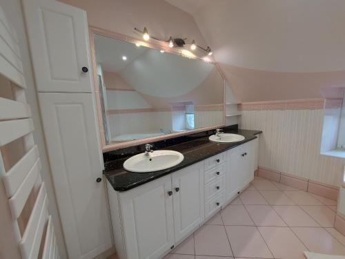 une salle de bain avec deux lavabos et un grand miroir dans l'établissement Le gîte du Cormier, à Saint-Aubin-du-Désert