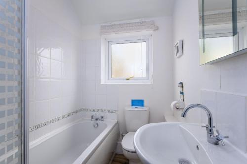 a white bathroom with a tub and a toilet and a sink at Cosy country cottage, nearby beaches attractions A55 in Llysfaen